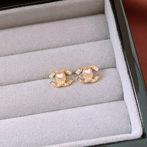 Macro detail of 14k gold plated double C logo earrings with diamonds and pink pearl