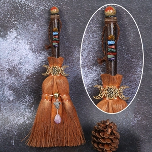 Close-up of witch broom with triple moon symbol, colorful stones and purple crystal