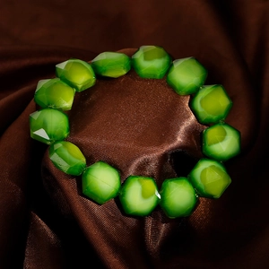 Detailed macro shot of green faceted crystal beads on a silk background for the bracelet
