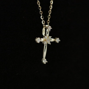 Detailed macro view of a gold S925 sterling silver cross pendant with clear gemstones