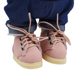Close-up of pink suede doll sneakers with bow laces paired with blue cuffed jeans