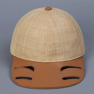 Detail of the woven straw crown and brown leather brim with cutout slots on the baseball cap