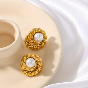 Vintage gold twist hoop earrings with white pearl center on white silk fabric background
