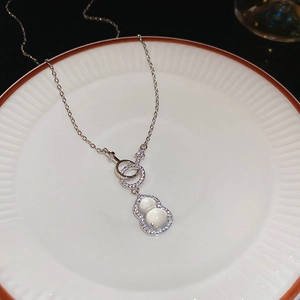 Detail of silver gourd pendant featuring a milky gemstone and shimmering zircon halo
