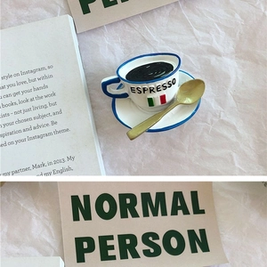 Macro shot of 3D espresso cup and saucer fridge magnet with decorative spoon and card
