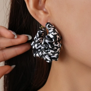 Detail of fabric wrapped leopard print hoop earring worn by a model for fashion style