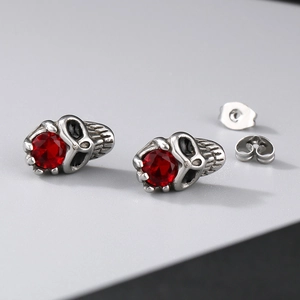 Macro shot of silver skull stud earrings with red crystal eyes and metal backings