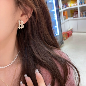 Sparkling gold letter B stud earring with inlaid crystals on a female model