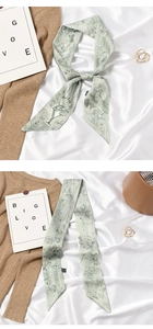 Detail of light green twilly scarf with floral prints tied as a bow on a wooden bag