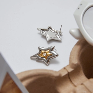 Detailed view of star-shaped stainless steel earrings with crystals on a stylish tray