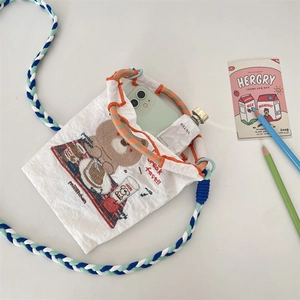 Détail du mini sac blanc avec broderie d'ours et bandoulière en corde tressée colorée