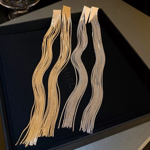 Detail of long gold and silver tassel earrings with triangle studs in a black box