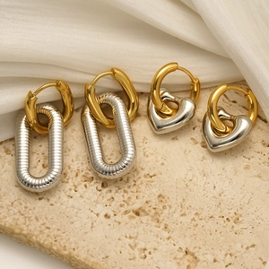 Two-tone gold and silver heart-shaped and oval hoop earrings on a stone surface