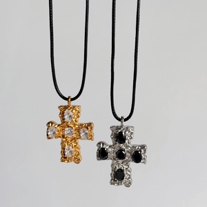 Detail of gold and silver cross pendants with textured finish and black cord chain