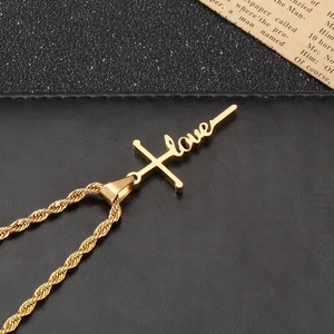 Makroaufnahme der goldenen Kordelkette mit Kreuz und LOVE-Buchstabenanhänger-Detail