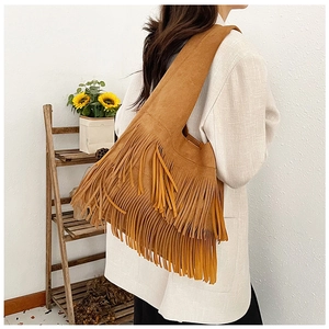 Close-up of a brown suede tote bag featuring bohemian layered fringes on the side