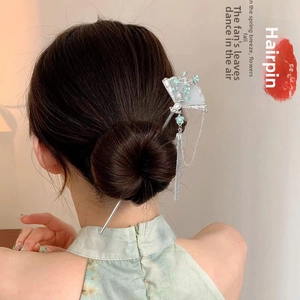 Detailed view of silver-toned fan hair pin with pearls and long tassel for bun hairstyle