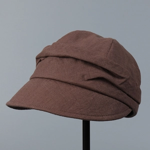 Detailed view of dark brown linen duckbill cap showing retro layered pleats and fabric texture