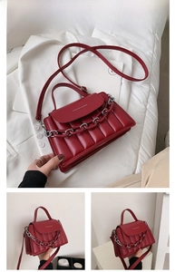 Detail of red quilted PU leather crossbody bag with silver plastic chain and brand lettering