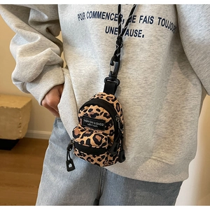 Detailed view of mini leopard print crossbody bag worn as a street style accessory