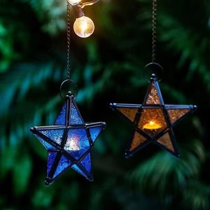 Close-up of hanging blue and yellow star-shaped glass lanterns with glowing candles