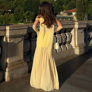Detail of elegant pale yellow long dress with open back design and matching sheer gloves