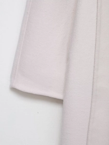 Detail of wool blend coat showing high-quality stitching on sleeve and front placket