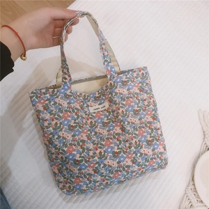 Borsa in tela a fiori con zip ed etichetta 'simple wish' mostrata portata a mano in foto