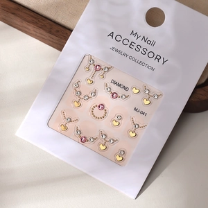 Macro view of MJ-041 nail art sticker with gold hearts and pink crystals on card
