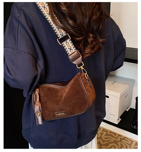 Detail of dark brown suede shoulder bag featuring a geometric patterned wide strap