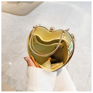 Detailed view of heart-shaped gold acrylic clutch bag with metallic mirror finish and handle