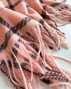 Detail view of pink and dark brown plaid scarf showing soft texture and tassel fringe