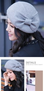 Detail view of a light gray wool beret featuring a stylish decorative bow ornament
