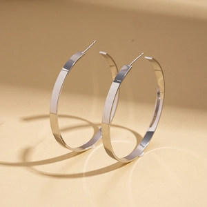 Close-up of glossy geometric silver hoop earrings with high-polished metallic finish