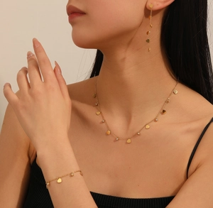 Detailed view of golden heart jewelry set with necklace earrings and bracelet on model