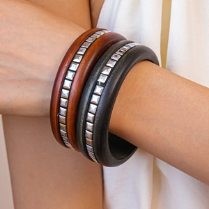 Vue détaillée d'un large bracelet en bois avec rivets métalliques au poignet féminin