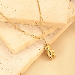 Close-up of golden bear pendant with embossed pattern and textured link chain necklace