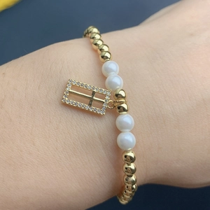 Detailed view of handmade beaded bracelet with golden beads and a cross pendant