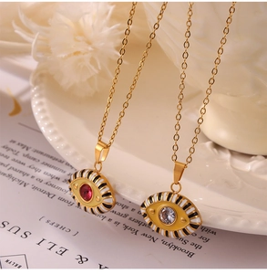 Close-up of golden Evil Eye pendants with red and clear crystals on white ceramic plate