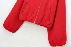 Detailed view of the red bomber jacket hem, metal zipper, and soft textured fabric