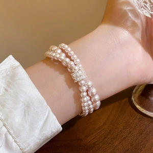 Close-up of triple-layer pink pearl bracelet with a sparkling crystal-encrusted rectangular clasp