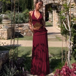 Detail of dark red two-piece set featuring halter crop top and high-waisted pleated maxi skirt