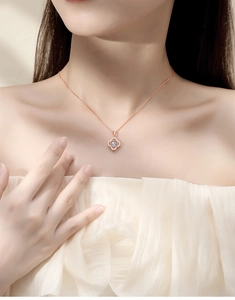 Close-up of rose gold four-leaf clover pendant with sparkling crystal on female neck