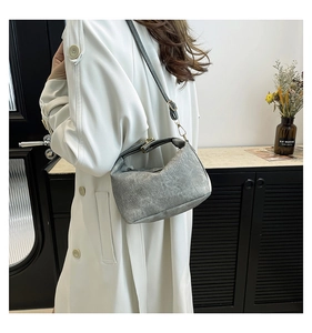 Detailed view of the gray textured shoulder bag worn by a model in a minimalist setting