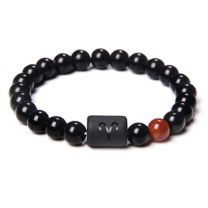 Detail of Aries constellation bracelet with black obsidian beads and red accent stone