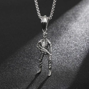 Macro shot of silver soldier pendant with rifle details on black textured background