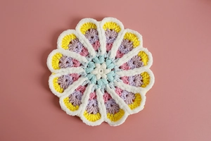 Macro detail of multi-color handmade crochet floral coaster with intricate yarn texture