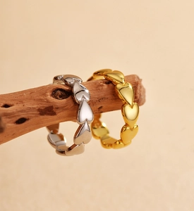Detail of silver and gold heart-shaped rings hanging on a natural wooden branch