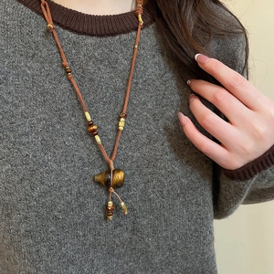 Detail of tiger eye stone gourd pendant on a long ethnic necklace with wooden beads