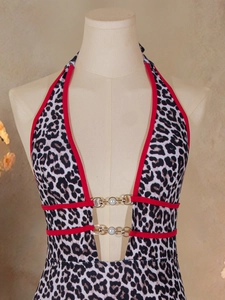 Close-up of leopard print swimsuit with red trim and pearl-accented gold buckles